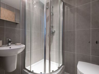 A bathroom with a corner shower cubicle a sink with a faucet and a toilet at Atlantis in St Ives