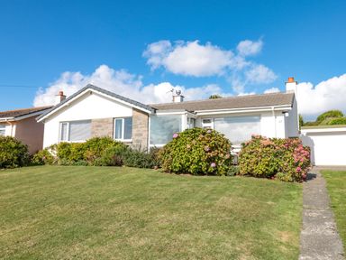 A single story house with shrubs and grass lawn at 33 Weymouth Park in Hope Cove