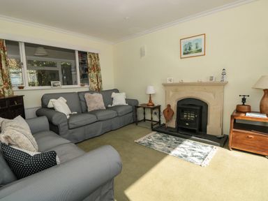 A living room with grey sofas a fireplace a small rug and wooden furniture at 33 Weymouth Park in Hope Cove
