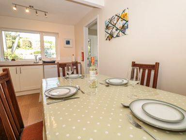A dining table set with plates glasses and utensils in a kitchen at 33 Weymouth Park in Hope Cove