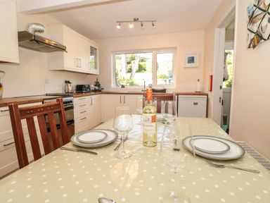 A kitchen with a dining table set with plates glasses and a bottle of wine at 33 Weymouth Park in Hope Cove