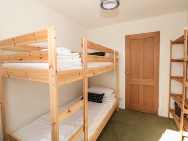 A bedroom with wooden bunk beds and shelving unit at 33 Weymouth Park in Hope Cove