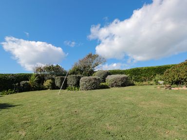 A garden with trimmed bushes and a clothesline under a blue sky at 33 Weymouth Park in Hope Cove