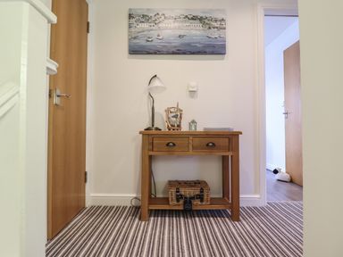 A wooden table with drawers and decorative items on top between two wooden doors at Harbour View in Porthmadog