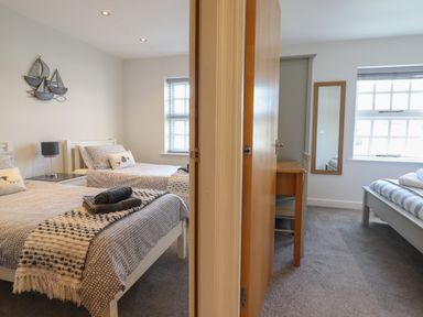 Two adjacent bedrooms separated by a wall each with a bed a window and a wooden door Harbour View Porthmadog