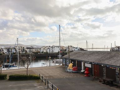 A marina with boats docked near residential buildings and a maritime museum at Harbour View in Porthmadog