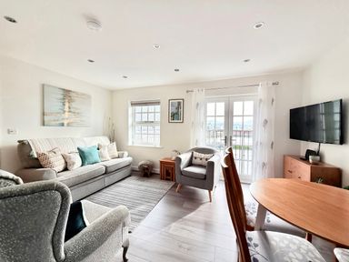 A living room with sofa, armchair, table and tv at Harbour View in Porthmadog