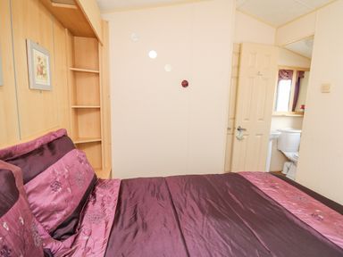 A bedroom with a bed and a door leading to a bathroom at The Lodge in Pontyates