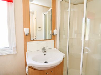 A bathroom with a sink cabinet mirror wall lights and a shower enclosure at The Lodge in Pontyates