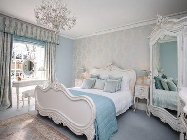 A bedroom with a bed a vanity table and a large wardrobe mirror at Tal Gwynedd in Dwyran near Newborough
