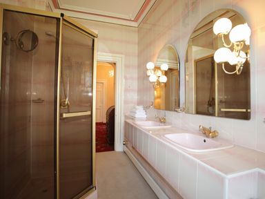 A bathroom with a shower enclosure and double sinks with mirrors and lights at Tal Gwynedd in Dwyran near Newborough