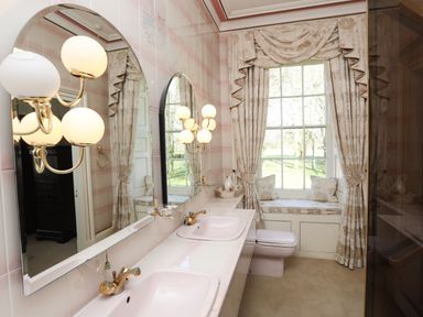 A bathroom with a double sink and gold fixtures and a window seat with curtains at Tal Gwynedd in Dwyran near Newborough