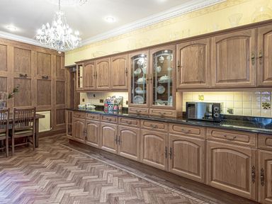 A kitchen with wooden cabinets a microwave on the counter and a dining table with chairs at Tal Gwynedd in Dwyran near Newborough