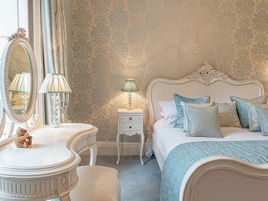 A bedroom with a bed side table a dressing table with mirror and lamps at Tal Gwynedd in Dwyran near Newborough