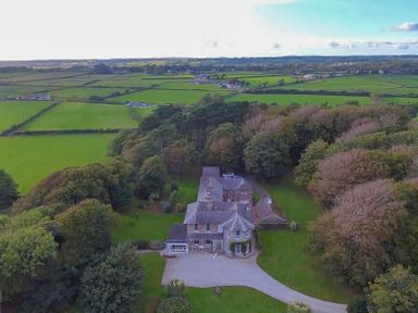 An aerial view of a large house surrounded by trees and fields at Tal Gwynedd in Dwyran near Newborough