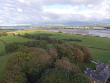 Aerial view of green fields trees a river and buildings at Tal Gwynedd in Dwyran near Newborough