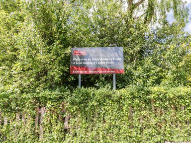 A sign welcoming visitors to Mary Arden's Farm surrounded by greenery at Heath Cottage in Stratford-Upon-Avon