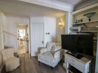 A living room with an armchair and TV stand at Heath Cottage in Stratford-Upon-Avon