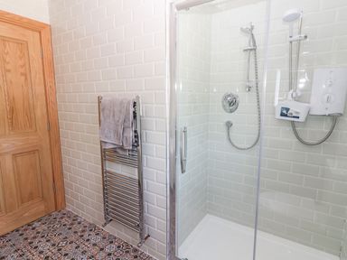 A bathroom with a glass shower enclosure and a towel rack with towels at Lack Cottage in Annascaul near Camp County Kerry