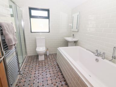 A bathroom with a bathtub sink toilet shower and patterned tiled floor at Lack Cottage in Annascaul near Camp County Kerry