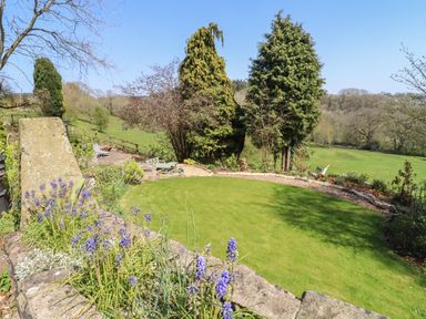 A garden with green lawn purple flowers and trees with a view of fields at The Tack Room in Lydney