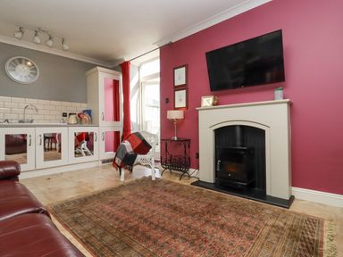 A living room with a fireplace TV wicker chair cabinet and rugs at The Tack Room in Lydney