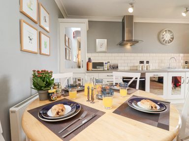 A kitchen with a round dining table set for breakfast with pastries and orange juice at The Tack Room in Lydney
