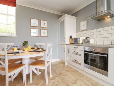 A kitchen with a dining table set for breakfast and white cabinets at The Tack Room in Lydney