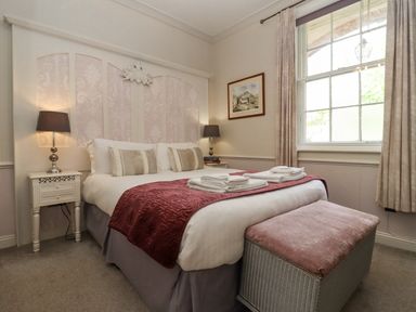 A bedroom with a double bed and folded towels on a bench by the window at The Tack Room in Lydney