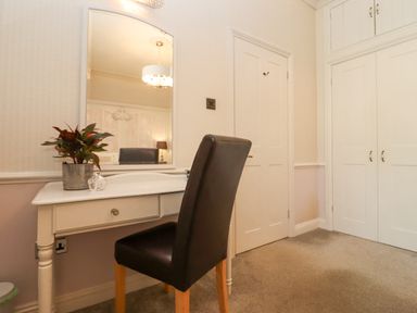 A dressing table with a mirror and a black chair next to white doors in a room at The Tack Room in Lydney