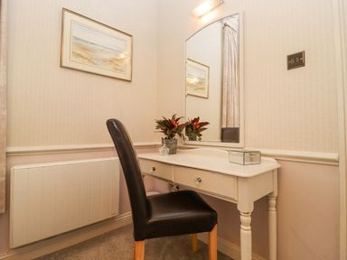 A dressing table with a mirror and chair a painting on the wall and a radiator at The Tack Room in Lydney