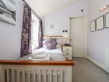 A bedroom with a bed bedside table lamp and framed pictures on the wall at The Tack Room in Lydney
