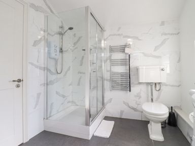 A bathroom with a shower enclosure toilet and heated towel rail at The Tack Room in Lydney
