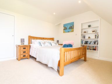 A bedroom with a wooden bed and side tables with lamps along with built in shelves at Higher Kernick View in Helland near Blisland