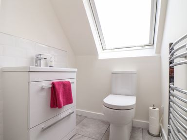 A bathroom with a white sink cabinet a pink towel a toilet and a skylight window at Higher Kernick View in Helland near Blisland