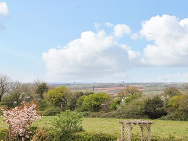 A countryside landscape view with trees fields and a wooden garden arch at Higher Kernick View Helland near Blisland