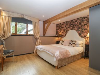 A bedroom with a double bed and floral wallpaper at The Courtyard - Hilltop Barn in Winterborne Zelston near Wareham