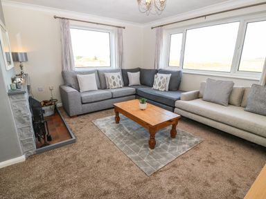 A living room with two sofas a wooden coffee table and a fireplace at Windy Ridge in Trearddur Bay