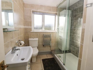 A bathroom with a toilet sink shower and window at Windy Ridge in Trearddur Bay