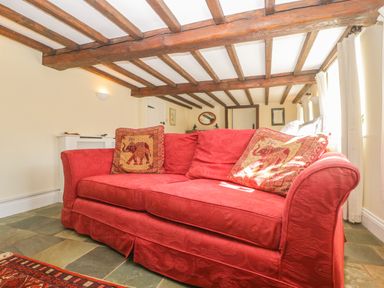 A red sofa with patterned cushions and wooden beam ceiling at Field View in Curland near Taunton