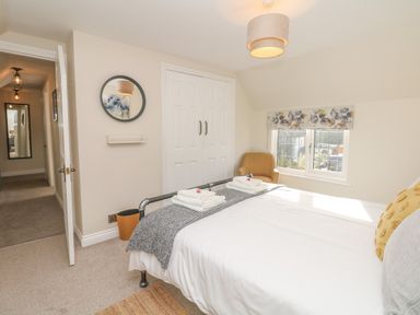 A bedroom with a bed and folded towels near a window and an armchair at Pumphouse Cottage in Uffculme