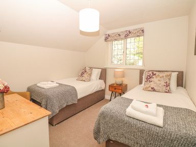 A bedroom with two single beds bedside table and lamp at Pumphouse Cottage in Uffculme
