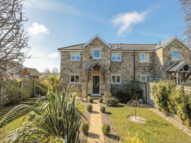 A stone house with a front garden and a paved path leading to the door at Cushat House Stamford near Embleton