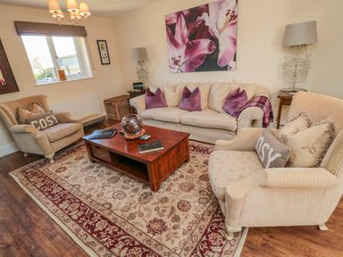 A living room with armchairs and a sofa around a wooden coffee table at Cushat House Stamford near Embleton