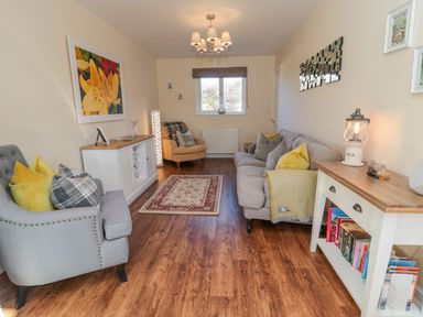 A living room with armchairs sofa rug and a console table with books at Cushat House Stamford near Embleton