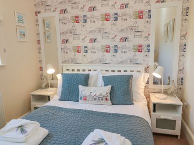 A bedroom with a double bed two bedside tables with lamps and tall mirrors at Cushat House Stamford near Embleton