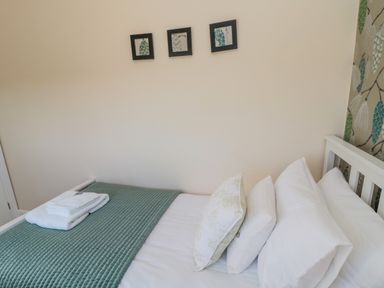 A bed with white pillows and folded towels on a green quilt in a bedroom at Cushat House Stamford near Embleton