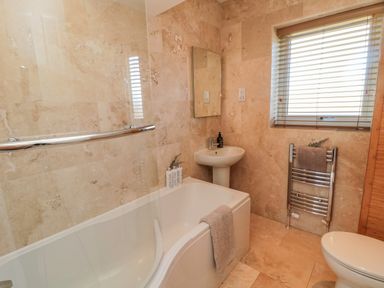 A bathroom with a bathtub sink radiator toilet and window blinds at Cushat House Stamford near Embleton