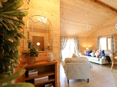 A living room with wooden walls curtains sofas and a round dining table at The Larches in Van near Llanidloes
