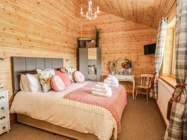 A bedroom with a bed with pillows and folded towels and wooden walls at The Larches in Van near Llanidloes